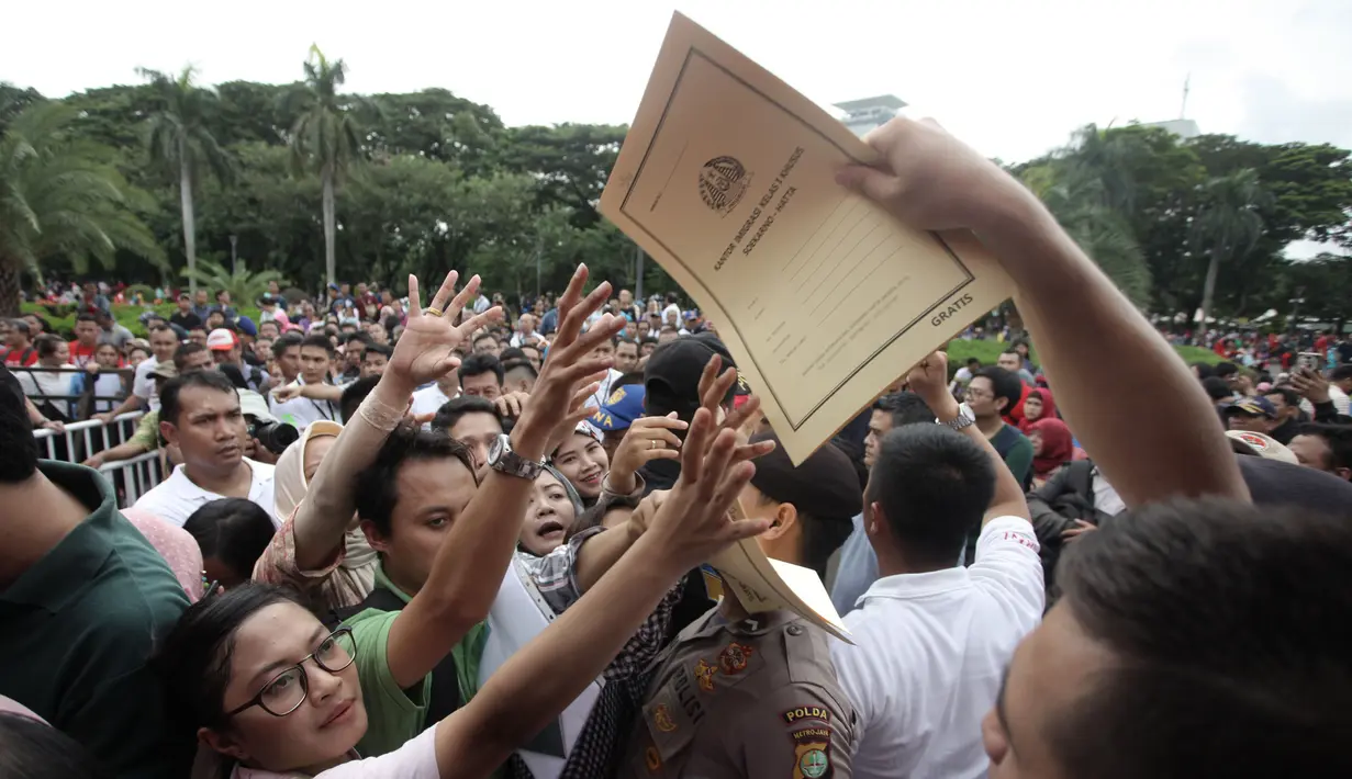 Warga berebut formulir untuk membuat paspor dalam acara Festival Keimigrasian 2018 di Lapangan Barat Daya Monas, Jakarta, Minggu (21/1). Dalam acara ini panitian menyediakan 1.600 formulir. (Liputan6.com/Arya Manggala)