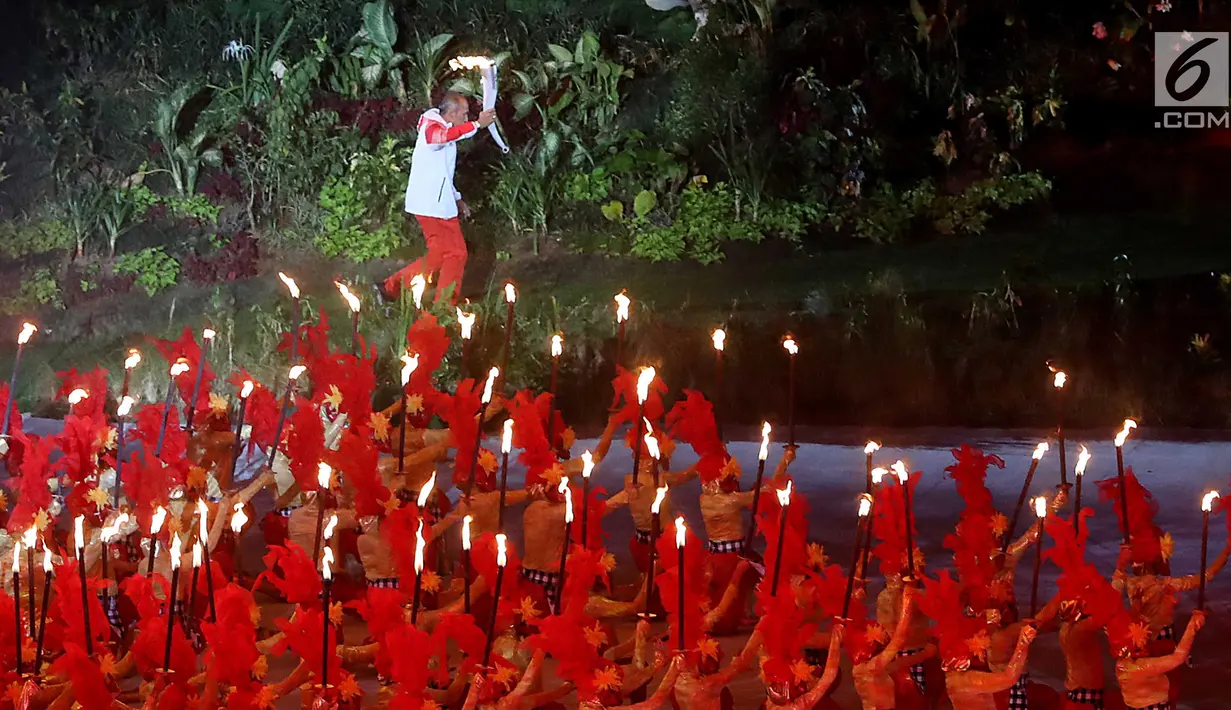 Peraih dua medali emas Asian Games 1978 dan dua medali emas Asian Games 1982 Yustedjo Tarik membawa obor Asian Games 2018 saat pembukaan di Stadion Utama Gelora Bung Karno (SUGBK), Jakarta, Sabtu (18/8). (Liputan.com/Fery Pradolo)