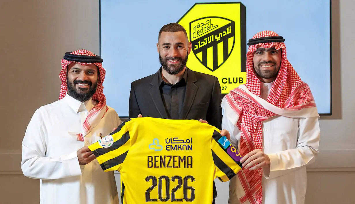 Pemain baru Al-Ittihad, Karim Benzema (tengah) berpose memegang jerseynya pada 6 Juni 2023. Kepindahan Benzema ke Arab Saudi cukup mengagetkan. Ia memilih hengkang dari Real Madrid setelah kontrak sang pemain habis yang membuatnya berstatus bebas transfer. Penyerang Timnas Prancis tersebut dikontrak Al-Ittihad selama tiga tahun. (AFP/Saudi Pro League/Jorge Ferrari)