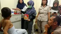 Bocah korban penganiayaan berusaha duduk ketika petugas medis datang untuk memeriksanya. (Liputan6.com/M Syukur)