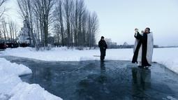 Pendeta Ortodoks memimpin di atas danau es dalam prosesi perayaan Epifani Ortodoks di Minsk, Belarusia (19/1/2016). Perayaan ini diwajibkan mandi dalam kolam berisi air suci, dalam kondisi cuaca apapun. (REUTERS/Vasily Fedosenko)