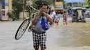 Seorang pria membawa sepeda menyebrangi banjir setelah hujan lebat di Kota Candaba, Pampanga, Manila, Filipina (17/12). Sembilan orang tewas akibat bencana yang terjadi di Filipina. (REUTERS/Romeo Ranoco)