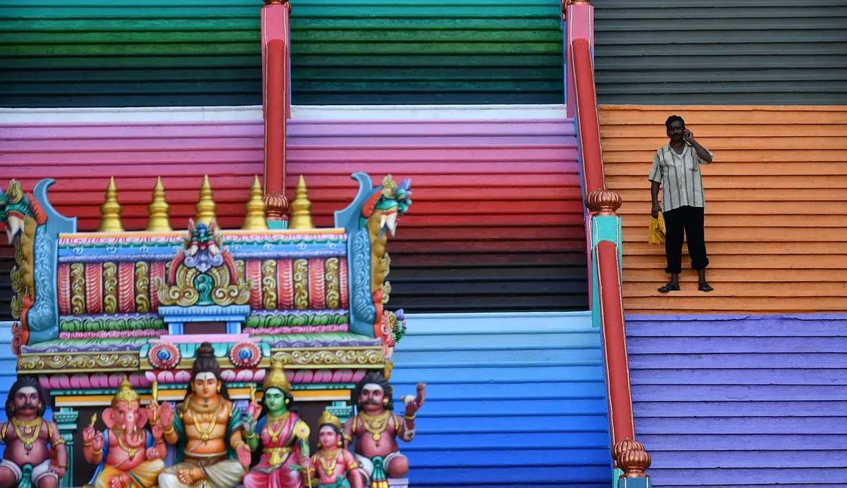 Pengunjung berdiri di tangga 272 langkah yang baru dicat, jalan untuk menuju kuil Batu Caves di Kuala Lumpur, Malaysia, 30 Agustus 2018. Pengecatan memungkinkan kompleks kehilangan status Warisan Dunia dari UNESCO.  (AFP/Manan VATSYAYANA)