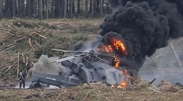 Seorang pilot yang selamat dari kecelakaan berjalan menjauh dari helikopter Mi-28N di Dubrovichi, Rusia, Minggu (2/8/2015). Helikopter  tersebut jatuh saat pertunjukan udara dan menewaskan satu dari dua orang pilot. (REUTERS/Maxim Shemetov)