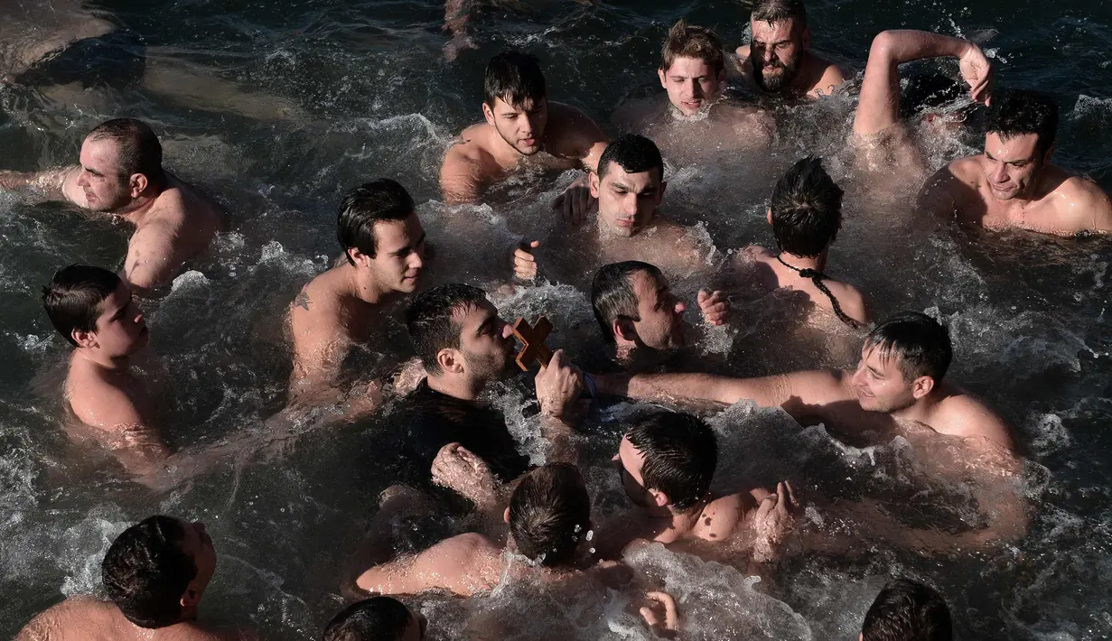 Sejumlah pria mengambil salib kayu yang dilemparkan ke laut saat restu upacara air menandai hari Epiphany Orthodox, di pelabuhan Thessaloniki, Yunani utara, (6/1). (AFP Photo/Sakis Mitrolidis)