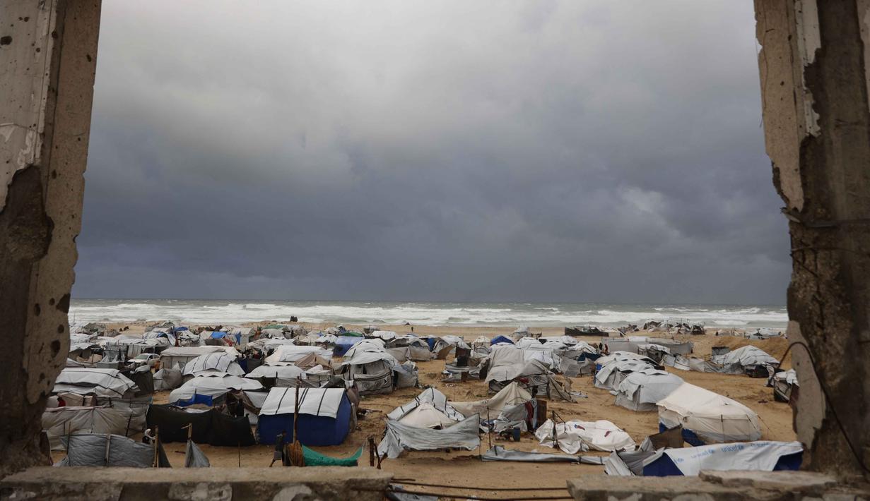 Badai musim dingin yang membawa angin kencang dan suhu ekstrem dilaporkan menghancurkan sejumlah tempat perlindungan. Tampak dalam foto, sebuah foto menunjukkan tenda-tenda penampungan keluarga-keluarga Palestina yang mengungsi, didirikan di sepanjang pantai Kota Gaza saat angin musim dingin yang kencang menerpa wilayah tersebut pada Selasa 13 Januari 2026. (Omar AL-QATTAA/AFP)