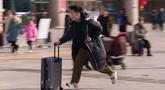 Seorang pria berlari sambil menyeret koper di stasiun kereta api saat orang-orang pulang kampung selama liburan Tahun Baru Imlek di Beijing, China, Selasa 10 Februari 2026. Gelombang migrasi penduduk tahunan terbesar China telah dimulai. (AP Photo/Vincent Thian)