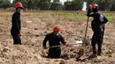 Gambar dari video pada 14 Juli 2019, pekerja Dewan Sipil Raqqa menggali kuburan massal berisi tulang belulang manusia di Raqqa, Suriah, 14 Juli 2019. Sejauh ini para pekerja telah menemukan 313 mayat dari kuburan massal yang ditemukan bulan lalu di dekat kota di Suriah utara tersebut. (AP Photo)