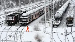 Seorang karyawan berjalan di terminal kereta barang saat salju lebat turun di Munich, Jerman, Rabu (9/1). Salju lebat menyelimuti kota-kota di Jerman. (Christof STACHE/AFP)