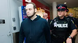 Joshua Boyle dikawal polisi setelah memberi keterangan kepada wartawan di bandara Toronto, Kanada (13/10). Boyle bersama istri dan ketiga anaknya dibebaskan oleh pasukan Pakistan dari tangan Taliban. (Nathan Denette / The Canadian Press via AP)