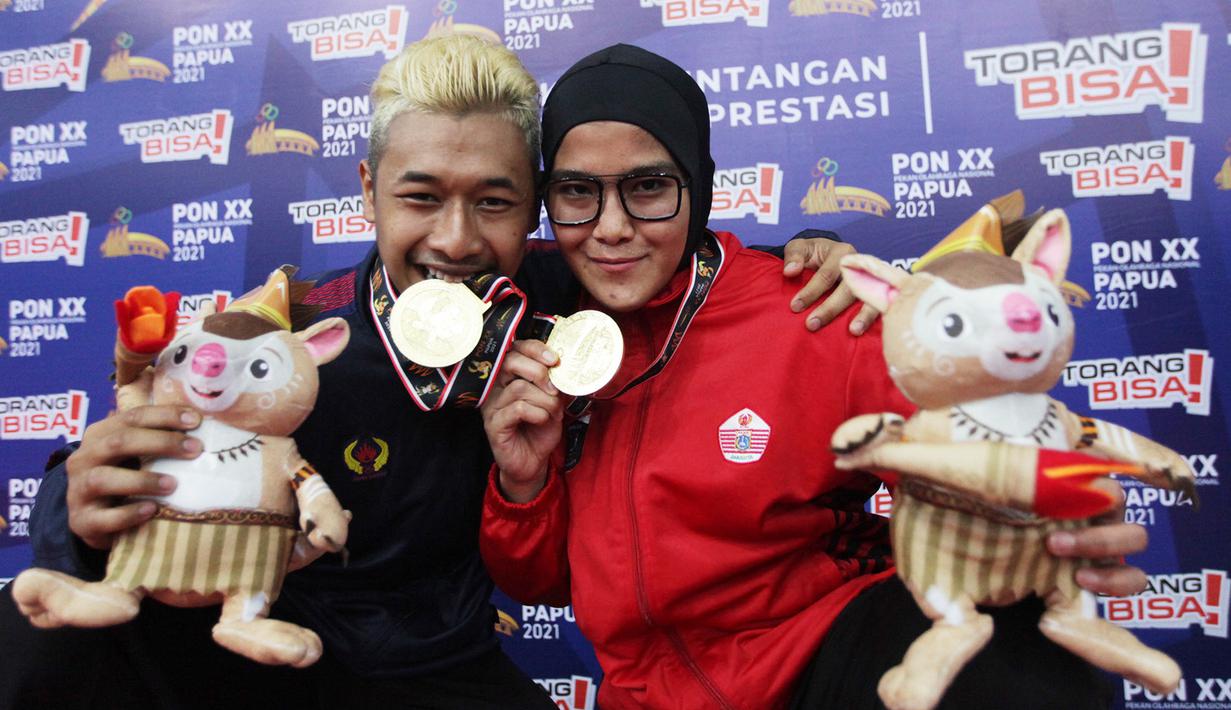Pasangan suami istri pesilat sama-sama peraih Medali Emas di kelas D  Tanding Putra Putri  dari Jawa Barat Hanifan Yudani Kusumah dan Pipiet Kamelia dari DKI Jakarta berfoto bersama pada PON XX PAPUA  di GOR Toware (12/10) Jayapura. (FOTO; PB PON XX PAPUA/TATAN AGUS RUSTANDI)