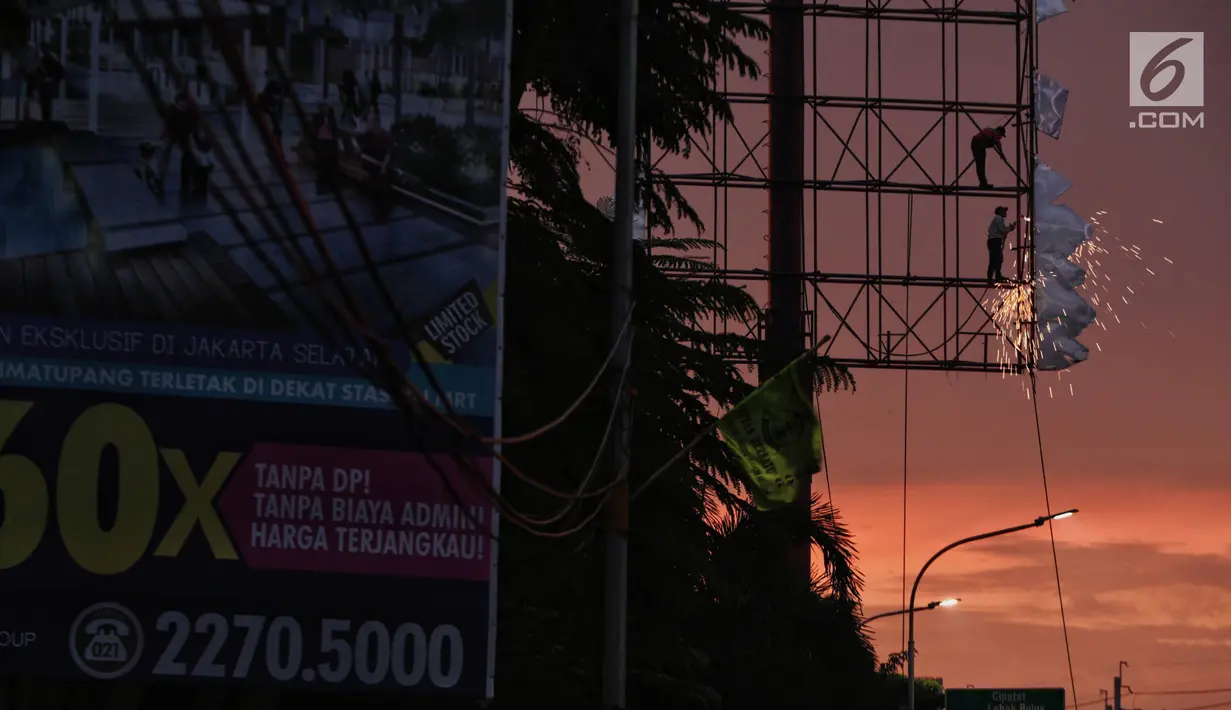 Dua pekerja memotong papan reklame yang telah tidak digunakan di kawasan Jalan TB Simatupang, Jakarta, Senin (11/2). Pemerintah Provinsi DKI Jakarta menganggarkan Rp 11 miliar untuk penertiban reklame ilegal. (Liputan6.com/Faizal Fanani)