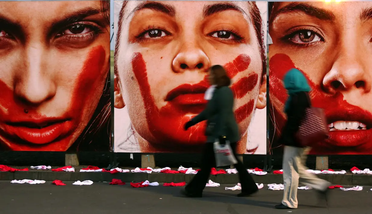 Warga berjalan disamping deretan foto wanita dengan wajah bercat merah di Sao Paulo Art Museum, Brasil , 10 Juni 2016. Ini juga sebagai protes organisasi non -pemerintah yang dinamakan Rio de Paz. (REUTERS / Paulo Whitaker)