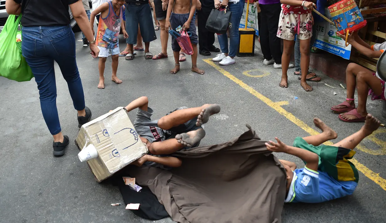 Aksi anak-anak jalanan saat melakukan tarian singa dengan kepala singa yang terbuat dari kardus saat menghibur pejalan kaki untuk menyambut Tahun Baru Imlek di Manila (4/2). (AFP Photo/Ted Aljibe)