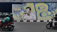 Pengendara melintas di depan mural berwajah mirip Presiden Joko Widodo atau Jokowi yang matanya tertutup masker di jembatan layang Pasupati, Kota Bandung, Rabu (25/8/2021). (Liputan6.com/Huyogo Simbolon)