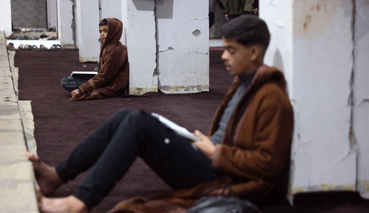 Umat Muslim membaca Al-Quran di Masjid Mahaba yang rusak selama perang Israel-Hamas di Khan Yunis, Jalur Gaza selatan pada Senin 16 Maret 2026. (Bashar Taleb/AFP)