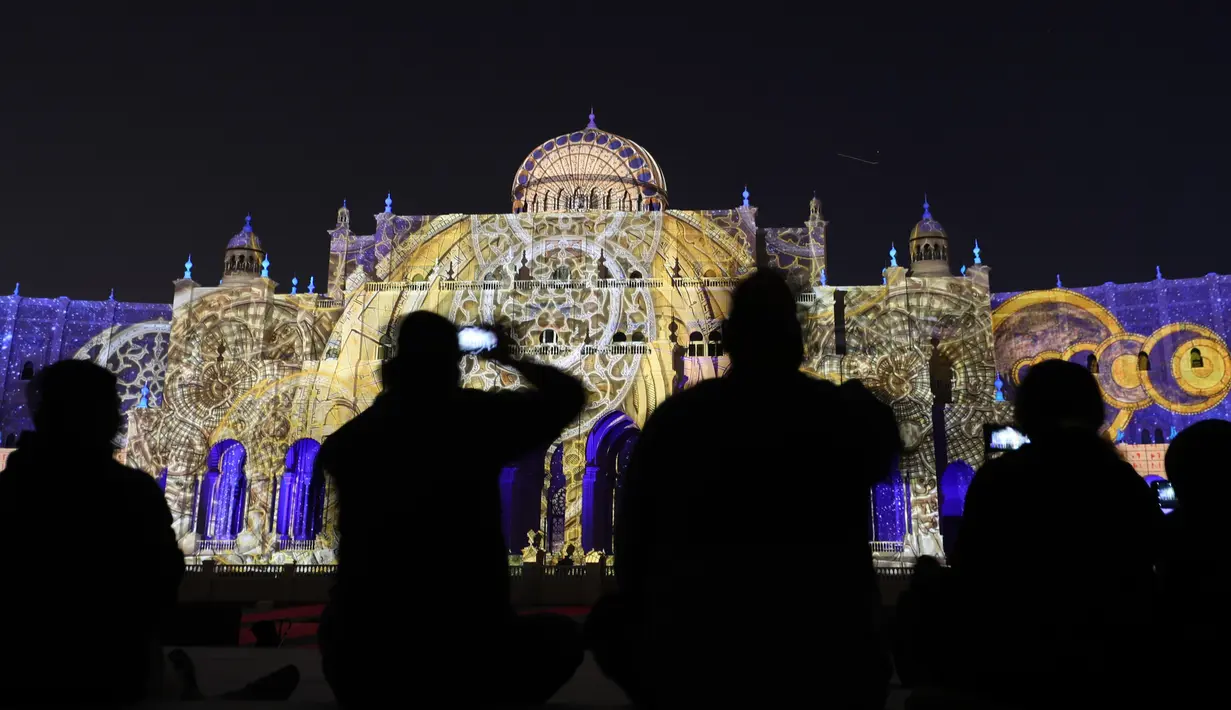 Pengunjung mengambil gambar bangunan ikonik kota Sharjah yang diterangi lampu warna-warni selama festival cahaya Sharjah di Uni Emirat Arab, 13 Februari 2019. Festival cahaya tahunan ini menampilkan kombinasi desain cahaya tiga dimensi. (KARIM SAHIB/AFP)