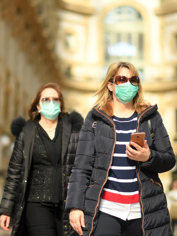 Dua wanita mengenakan masker berjalan di Milan, Italia (24/2/2020). Kepala Departemen Perlindungan Sipil sekaligus Komisaris Luar Biasa untuk Darurat Coronavirus, Angelo Borrelli mengatakan enam orang meninggal dan 222 lainnya teruji positif infeksi COVID-19 di Italia. (Xinhua/Daniele Mascolo)