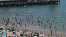 Para pengunjung bermain dan bersantai di bawah sinar matahari di Pantai Bournemouth, Selatan Inggris pada Selasa 26 Mei 2026, saat kondisi gelombang panas menyebar ke sebagian wilayah tenggara Inggris dan London. (JUSTIN TALLIS/AFP)