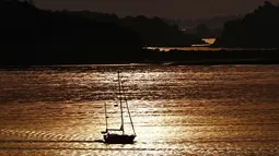 Sinar matahari pagi mewarnai perairan Teluk Casco ketika seorang pelaut mengemudikan kapalnya ke laut di Portland, Maine (21/8/2019). Ada dua teori tentang asal usul nama "Casco Bay". Aucocisco adalah nama Abenaki untuk teluk, yang berarti 'tempat kuntul'. (AP Photo/Robert F. Bukaty)