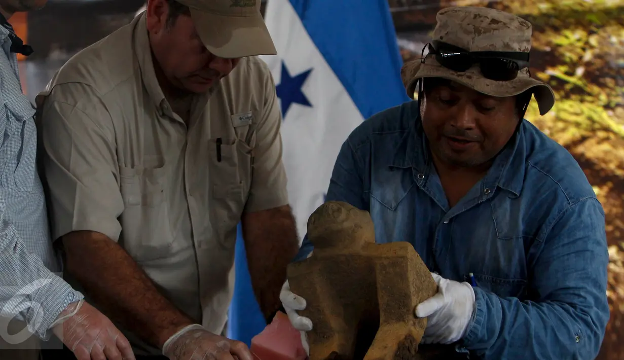 Presiden Honduras, Juan Orlando Hernandez (tengah) dan seorang arkeolog saat memamerkan benda kuno pada upacara di Catacamas, Honduras, (12/1). Benda - benda kuno ditemukan pada 2012 yang menyudut pada legenda "Kota Putih". (REUTERS / Jorge Cabrera)
