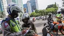 Petugas kepolisian lalu lintas saat menilang pengendara motor saat Operasi Zebra Jaya 2020 di kawasan Cawang, Jakarta, Senin (26/10/2020). Operasi Zebra Jaya dilaksanakan pada 26 Oktober-8 November 2020 untuk menekan jumlah pelanggaran lalu lintas. (Liputan6.com/Faizal Fanani)