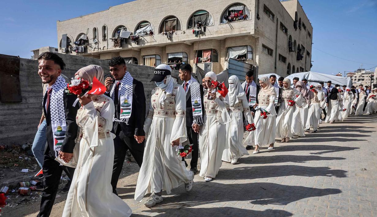 Puluhan pasangan pengantin Palestina mengikuti pernikahan massal yang digelar di kota Gaza, 11 Mei 2026. Tampak dalam foto, para pengantin Palestina berkumpul selama perayaan pernikahan massal untuk para pengantin Palestina yang diselenggarakan oleh Yayasan Bantuan Kemanusiaan Turki (IHH) di Kota Gaza pada 11 Mei 2026. (Omar AL-QATTAA/AFP)