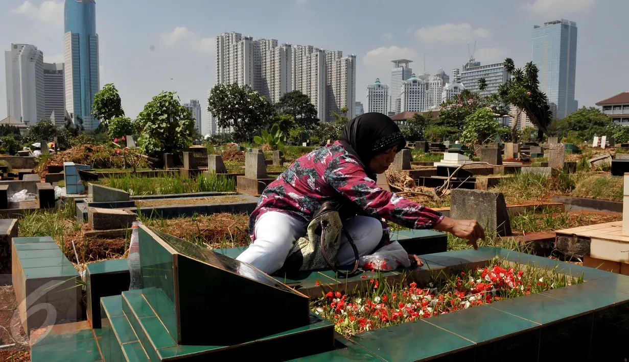 Seorang peziarah tampak menaburkan bunga di makam keluarganya di TPU Karet Bivak, Jakarta, Sabtu (18/7/2015). Ziarah kubur dilakukan umat muslim untuk mendoakan mendiang keluarga dan kerabat mereka yang telah meninggal. (Liputan6.com/JohanTallo)