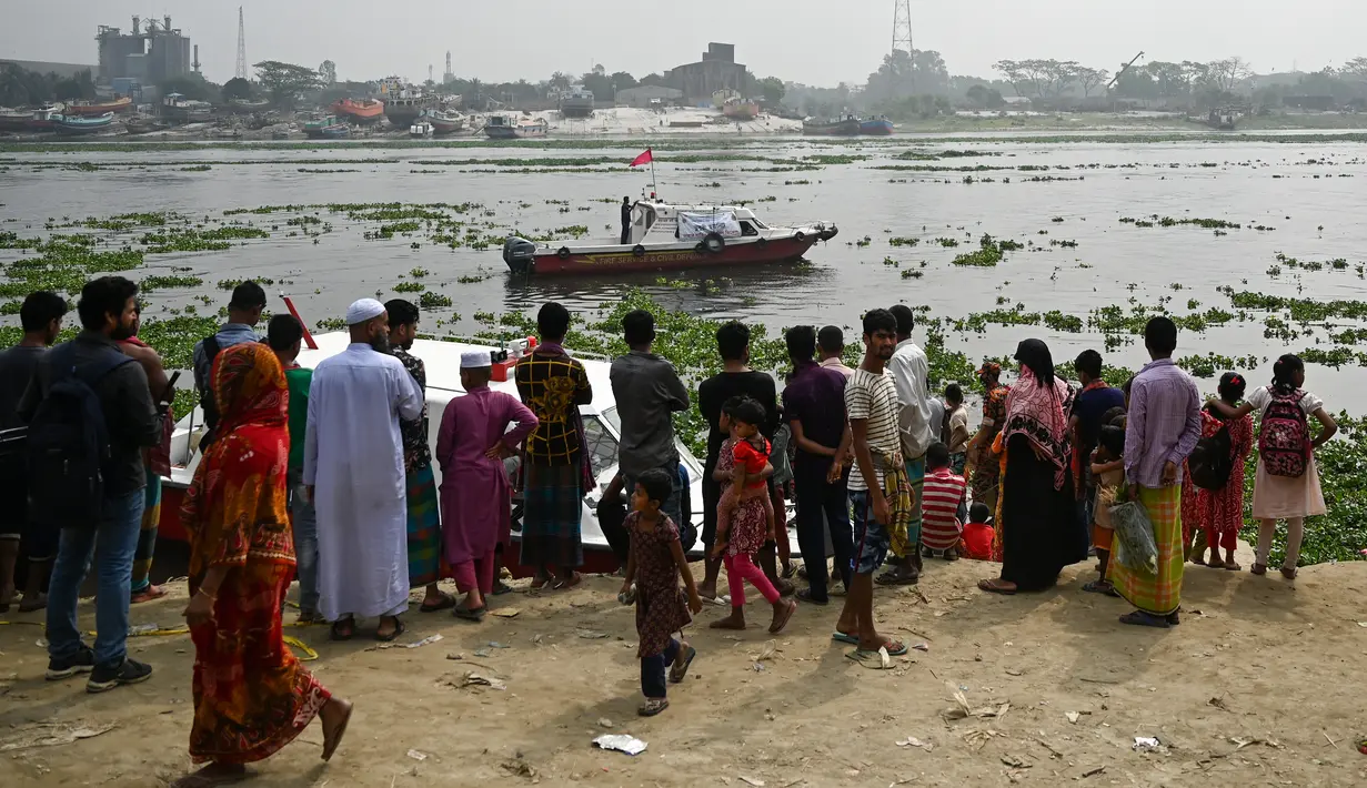 Orang-orang menyaksikan petugas pemadam kebakaran mencari korban kecelakaan feri di Sungai Shitalakshya di Narayanganj, Bangladesh (21/3/2022). Feri ML Afsar Uddin tenggelam di sungai setelah ditabrak kapal kargo. (AFP/Munir uz Zaman)