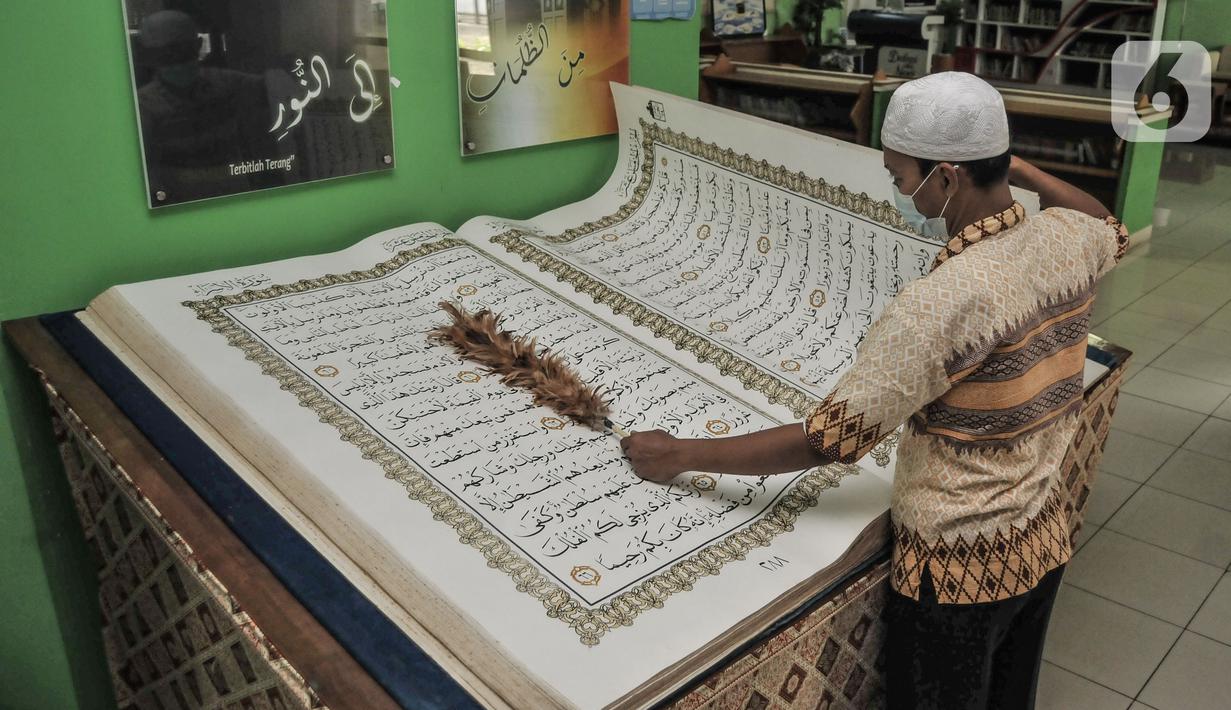 Petugas membersihkan Alquran raksasa koleksi Perpustakaan Jakarta Islamic Center (JIC), Jakarta Utara, Kamis (22/4/2021). Alquran raksasa tersebut merupakan pemberian dari Universitas Sains Alquran Wonosobo sebagai penghargaan atas berdirinya masjid JIC pada 2002. (merdeka.com/Iqbal S Nugroho)