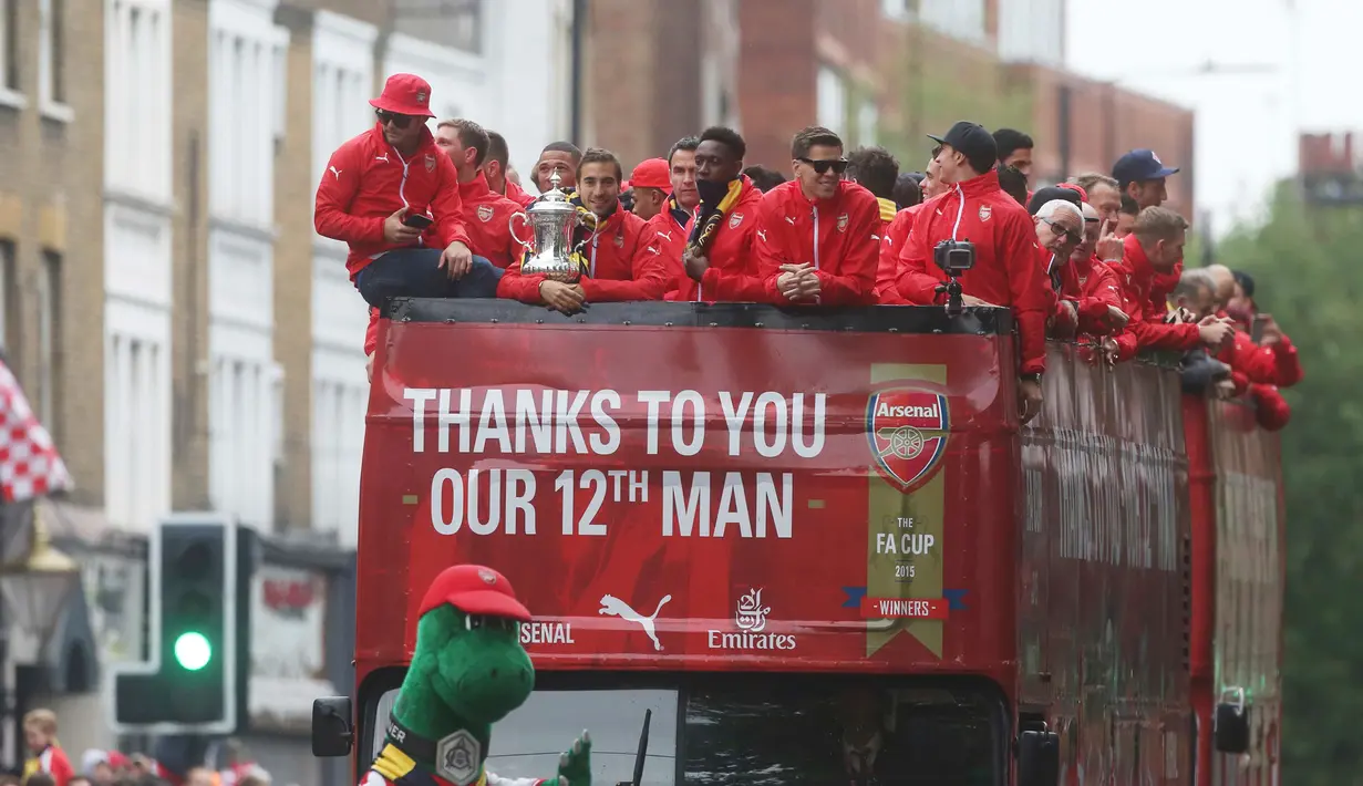 Para Pemain Arsenal berada diatas bus melakukan parade keliling kota untuk merayakan kemenangan usai meraih Piala FA di London, Inggris, (31/5/2015). Arsenal meeraih Trofi piala FA usai mengalahkan Aston Villa 4-0. (REUTERS/Neil Balai)