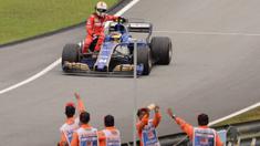 Pebalap Ferrari, Sebastian Vettel terpaksa menumpang mobil rekan senegaranya, Pascal Wehrlein setelah terlibat kecelakaan pada balapan Formula One Malaysia Grand Prix, Sepang, (01/10/2017). Vettel akhirnya finis pada posisi keempat. (AFP/Roslan Rahman)
