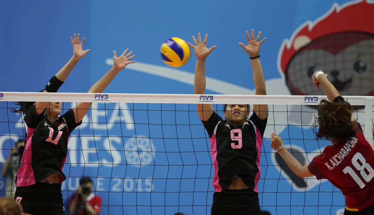 Dua pevoli putri Indonesia, Wilda SN (kiri) dan Aprilia M mencoba memblok smash pemain Thailand, Ajcharapom K di semifinal SEA Games ke-28 di OCBC Arena, Singapura, Minggu (14/6/2015). Indonesia kalah 1-3 dari Thailand. (Liputan6.com/Helmi Fithriansyah)
