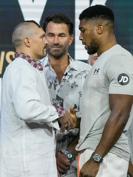 <p>Petinju Inggris Anthony Joshua (kanan) dan petinju Ukraina Oleksandr Usyk (tengah kiri) saling pandang saat penimbangan di King Abdullah Sports City, Jeddah, Arab Saudi, 19 Agustus 2022. Joshua dijadwalkan melawan juara bertahan Usyk dalam pertandingan ulang tinju kelas berat di Jeddah pada 20 Agustus. (AP Photo/Hassan Ammar)</p>