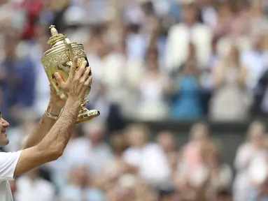 Petenis Swiss, Roger Federer, mengangkat trofi usai memastikan gelar juara dengan mengalahkan petenis Kroasia, Marin Cilic pada laga final Wimbledon 2017 di London, Minggu (16/7/2017). Federer menang 6-3, 6-1, 6-4 atas Cilic. (AFP/Daniel Leal-Olivas)