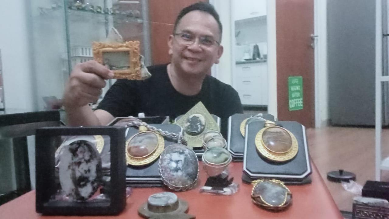 Muchlis menunjukkan batu koleksinya yang bergambar kepala orang dan satunya lagi kepala burung. (Foto: Bam Sinulingga/Liputan6.com)
