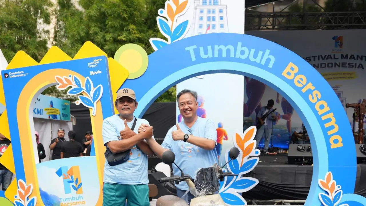 Direktur Utama Bank Mandiri Taspen, Panji irawan (kanan), menyerahkan hadiah sepeda listrik kepada salah satu nasabah yang hadir dalam perayaan HUT ke-11 Bank Mandiri Taspen di Surabaya.