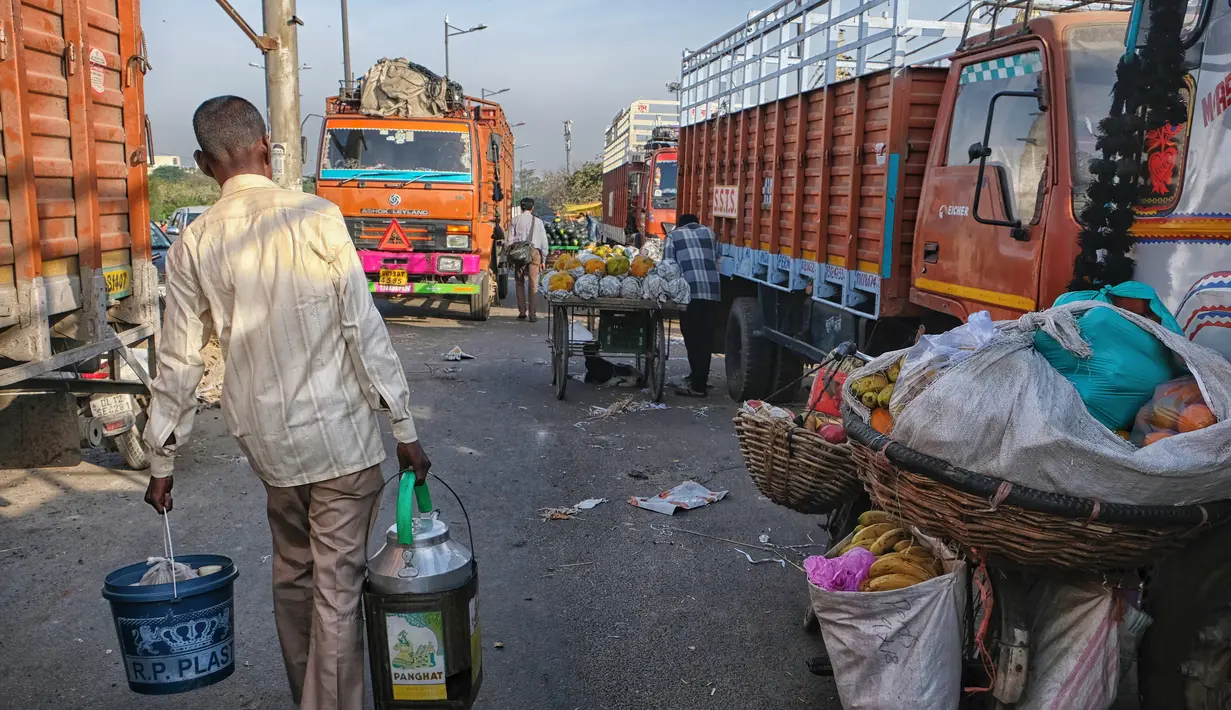 Penjual chai (teh) India berjalan melewati pasar grosir buah dan sayuran di New Delhi (27/3). Karena tidak semua orang mampu berbelanja di mal atau toko bermerek, sebagian besar penduduk lebih pergi ke pasar jalanan. Kualitas barang bervariasi dari pasar ke pasar. (AFP Photo/Noemi Cassanelli)