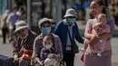Warga membawa anak-anak untuk berjemur di luar kompleks perumahan di Beijing, Selasa (6/9/2022). Kegiatan berjemur dilakukan untuk melawan virus COVID-19, karena sinar matahari dipercaya mampu membunuh virus dan bakteri, termasuk virus corona. (AP Photo/Andy Wong)