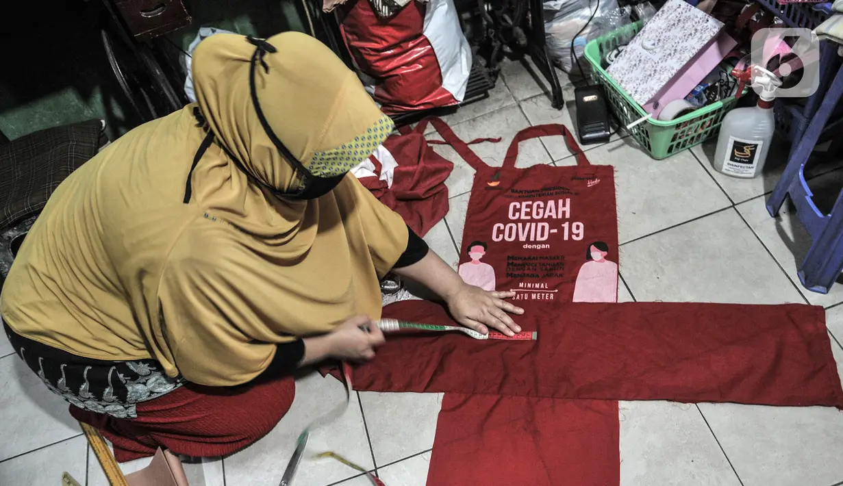 Siti Zahro (44) menggaris pola saat menyelesaikan pembuatan celemek dari tas bansos Covid-19 di industri jahit rumahan KG-Lupe Fashion, Salemba, Jakarta, Senin (16/11/2020). Dalam sehari Siti mampu memproduksi tiga buah celemek. (merdeka.com/Iqbal S. Nugroho)