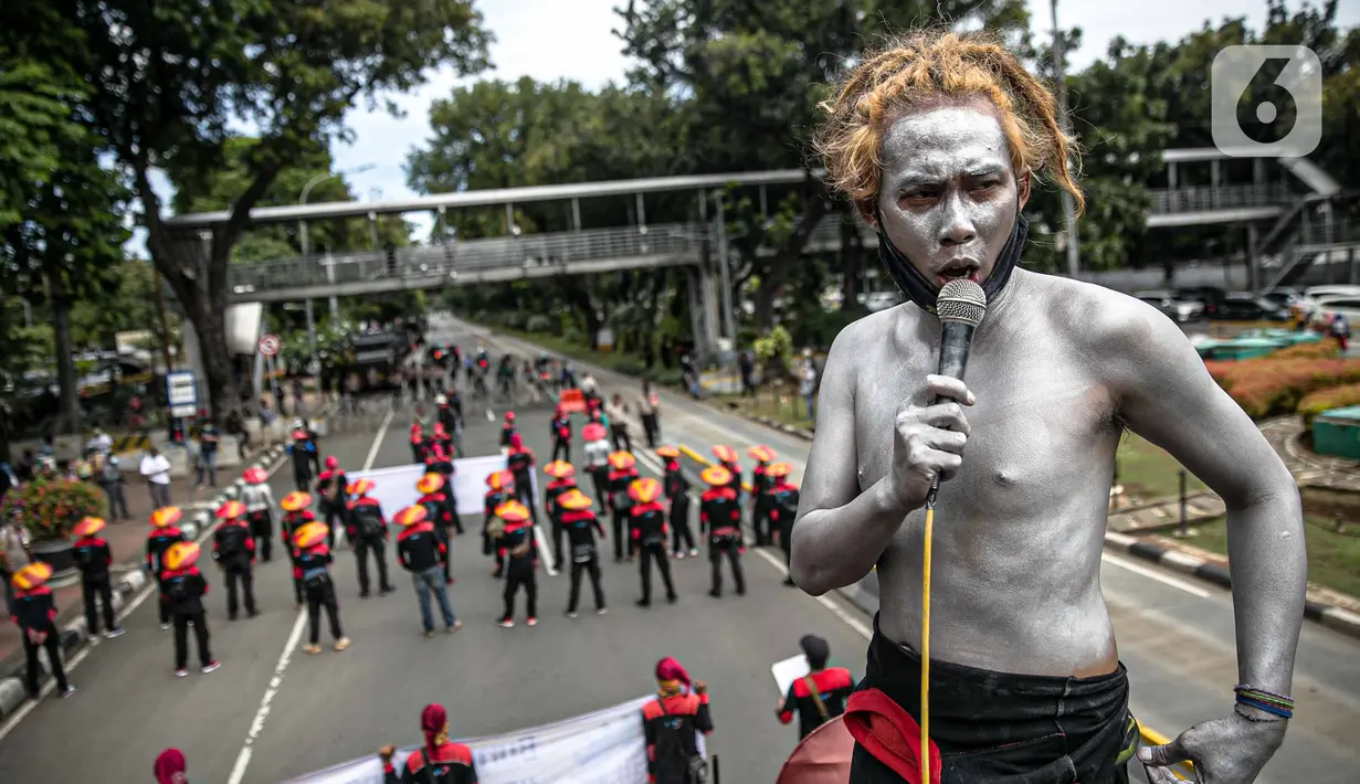Seorang buruh dengan tubuh di cat silver berorasi saat unjuk rasa di kawasan Patung Kuda, Jakarta, Rabu (16/12/2020). Aksi yang dihadiri ratusan buruh ini mematuhi imbauan pemerintah terkait protokol kesehatan. (Liputan6.com/Faizal Fanani)