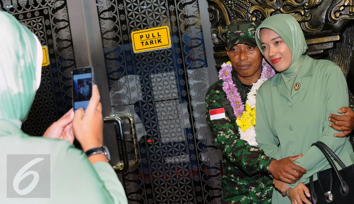 Personel TNI AD yang tergabung dalam kontingen AASAM berpose bersama pasangannya usai penyambutan kedatangan di Bandara Soetta, Banten, Senin (23/5/2016). TNI AD menjadi juara umum AASAM 2016 yang digelar di Australia. (Liputan6.com/Helmi Fithriansyah)