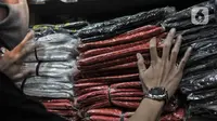 Abdullah (37) merapikan kantong plastik sekali pakai yang dijualnya di Pasar Tebet Barat, Jakarta, Selasa (30/6/2020). Jelang pemberlakuan larangan penggunaan plastik sekali pakai, Abdullah mengaku penjualan kantong kresek di tokonya menurun hingga 30 persen. (merdeka.com/Iqbal S Nugroho)