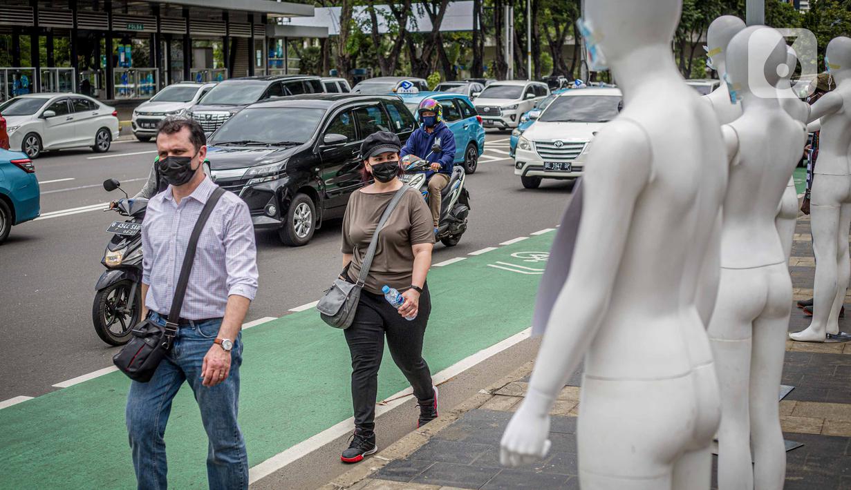 Pejalan kaki melintas di depan manekin yang dipajang dalam aksi di Polda Metro Jaya, Senin (21/3/2022). Aksi tersebut bentuk dukungan terhadap Haris Azhar dan Fatia Maulidiyanti saat menjalani pemeriksaan terkait kasus dugaan pencemaran nama baik Luhut Binsar Pandjaitan. (Liputan6.com/Faizal Fanani)