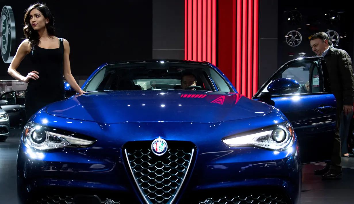 Model berpose di samping Alfa Romeo Giulia saat pameran North American International Auto Show 2017 di Detroit, Michigan, AS (9/1). Pameran ini diadakan dari tanggal 8 sampai 22 Januari 2017. (AFP Photo/Jim Watson)