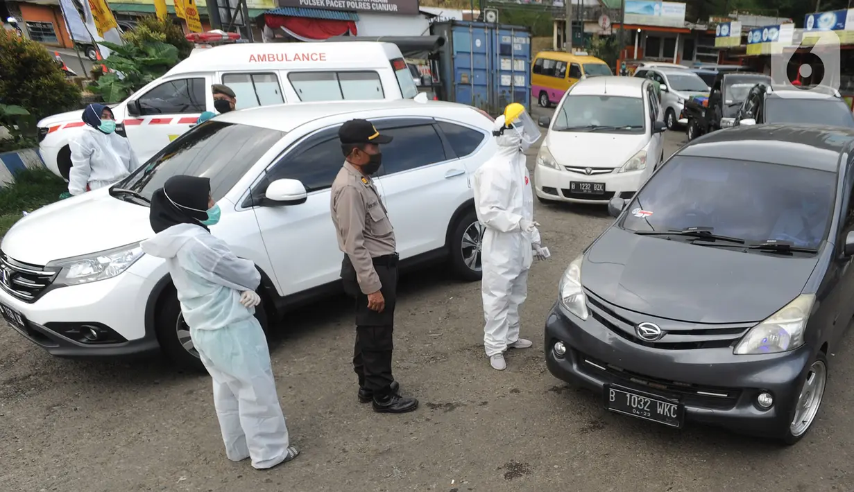 Petugas memeriksa surat keterangan lolos uji rapid test pada warga yang akan melakukan perjalanan di Pos Pam Puncak Pass, Cianjur, Minggu (17/5/2020). Mereka diperbolehkan melakukan perjalanan kecuali dilengkapi surat tugas atau  surat keterangan sehat dari pihak berwenang. (merdeka.com/Arie Basuki)
