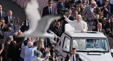 Seekor burung terbang melintas saat Paus Leo XIV menggunakan popemobile berkeliling Lapangan Santo Petrus Basilika di Vatikan, Minggu 18 Mei 2025. (Jacquelyn Martin/POOL/AFP)