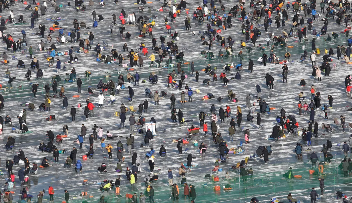 Peserta memancing ikan trout melalui lubang yang mereka buat di atas sungai beku di Hwacheon, Korea Selatan, Sabtu (5/1). Kontes ini merupakan bagian dari festival es tahunan yang menarik lebih dari satu juta pengunjung setiap tahun. (AP/Ahn Young-joon)