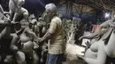 Perajin membuat patung Dewa Ganesha di sebuah bengkel di pinggiran Hyderabad, India, Rabu (18/8/2021). ​Patung ramah lingkungan yang dibuat jelang perayaan Ganesh Chaturthi tersebut dibuat dari lumpur, serat rami, dan bambu untuk mengurangi polusi air. (NOAH SEELAM/AFP)