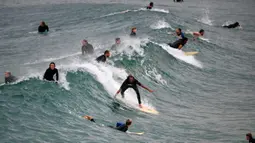 Orang-orang berselancar di Pantai Maroubra, Sydney (20/4/2020). Pihak berwenang di Sydney membuka kembali tiga pantai untuk aktivitas warga yang ingin berenang ataupun berselancar di tengah pembatasan sosial yang diberlakukan di tengah wabah corona (Covid-19). (AFP/Saeed Khan)